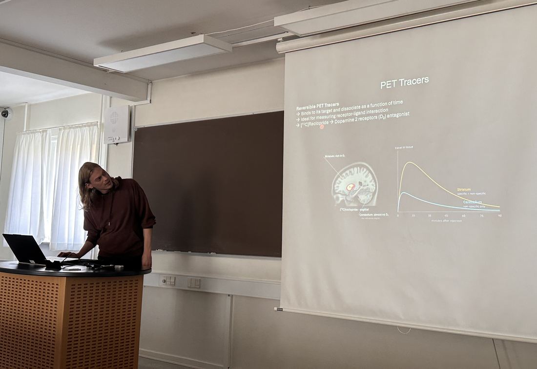 Frederik Gudmundsen teaching, in front of a slide on reversible PET tracers with [11C]raclopride as the example.